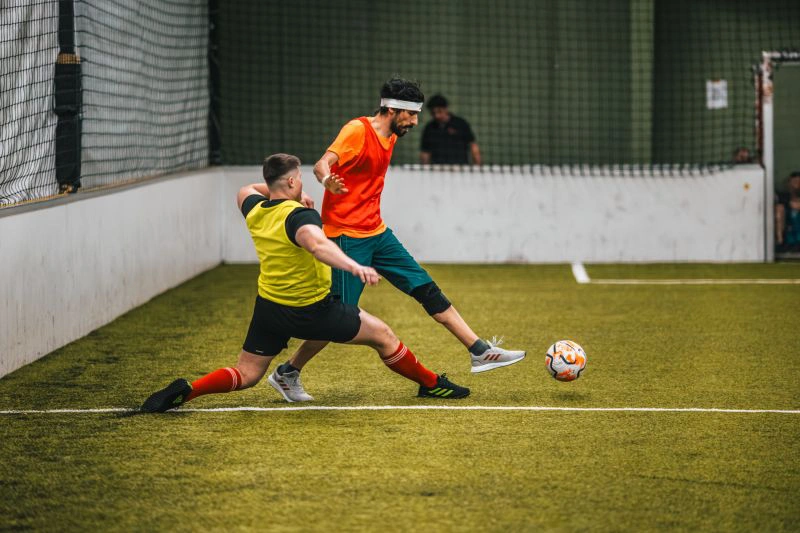Two players challenging for the ball at the indoor football tournament