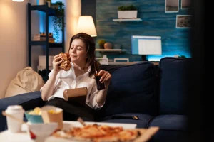 Woman enjoying a delivered burger on the sofa