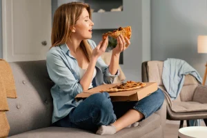 Woman eating a delivered pizza while watching TV
