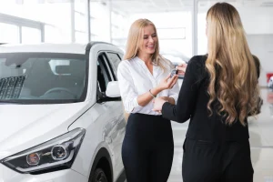 Customer receiving the key to her new car at a dealership